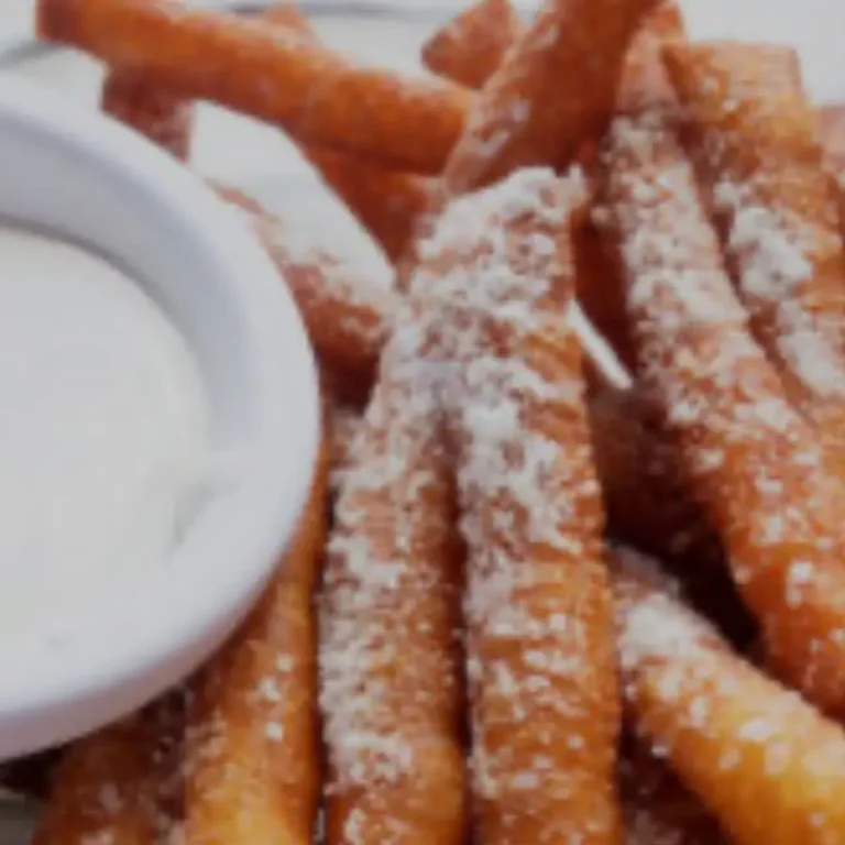 Sweet potato fries dusted with powdered sugar, served with a side of white dipping sauce
